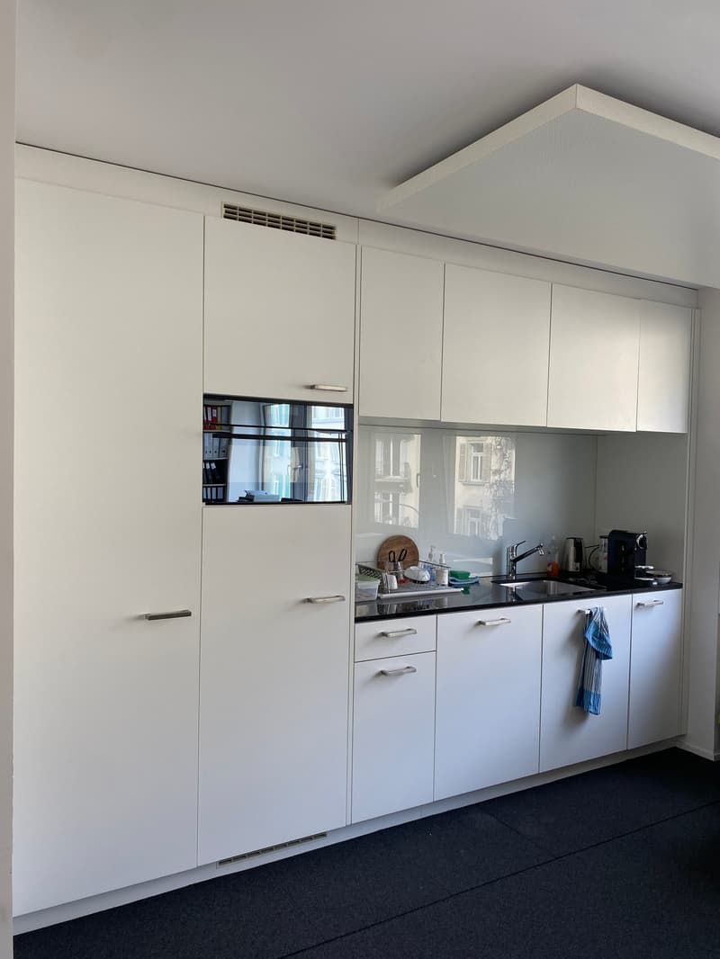 modern kitchen with white cabinets, black countertops, built-in dishwasher, built-in washing machine, sink with faucet, kitchenware on countertop