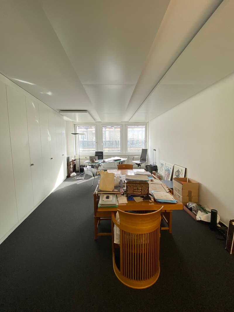 large open office space with desks, cabinets, and chairs, glass windows with balcony view, modern design, clean and empty