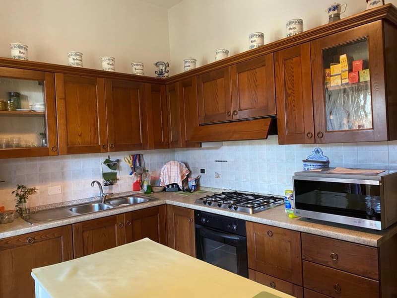 Wooden cabinets, tile backsplash, gas stove, oven, sink, countertops, kitchen utensils and appliances