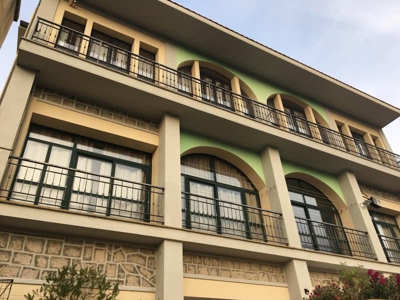 3-story apartment building with arched windows, balconies, and a stone facade