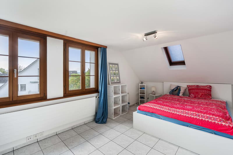 bedroom with bed, double glazed window, radiator, loft window, lamps