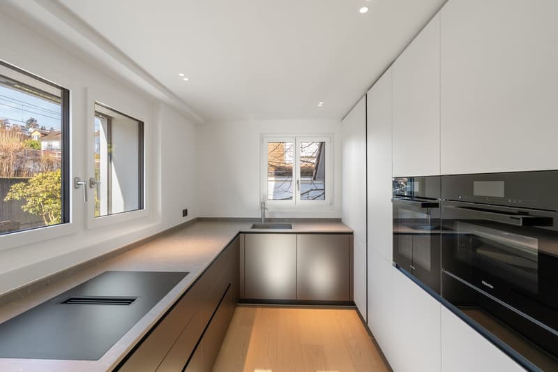 Modern kitchen with white cabinets, wooden floor, stainless steel countertops, modern appliances