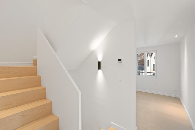 white walls, wooden floor, modern staircase with handrail, white ceiling, wall light, window
