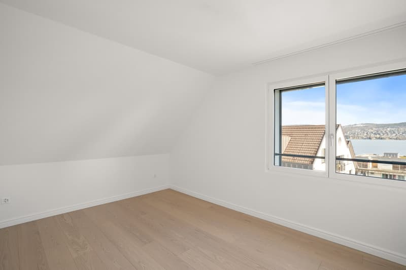 empty room, white walls, wooden floor, large window with view to lake and mountains