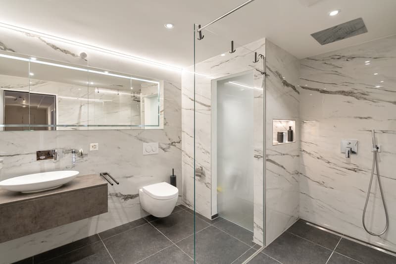 white marble wall, white oval sink, white toilet, white shower