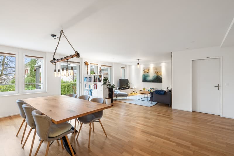large wooden table with 6 chairs, white walls, wooden floor, window with terrace, chandelier
