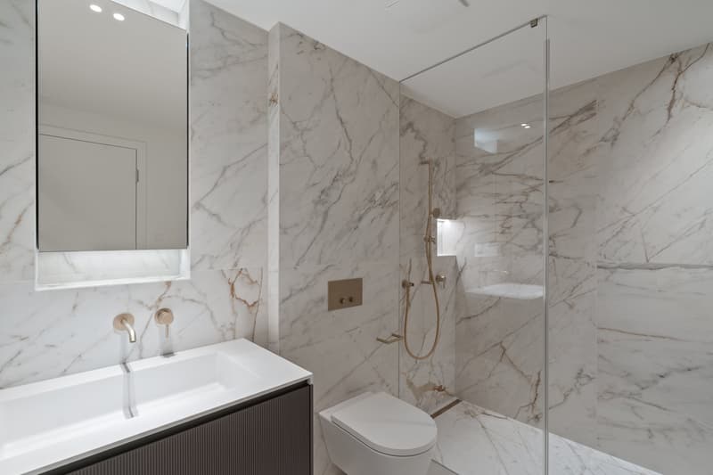 modern bathroom with marble walls, white sink, modern shower, white toilet
