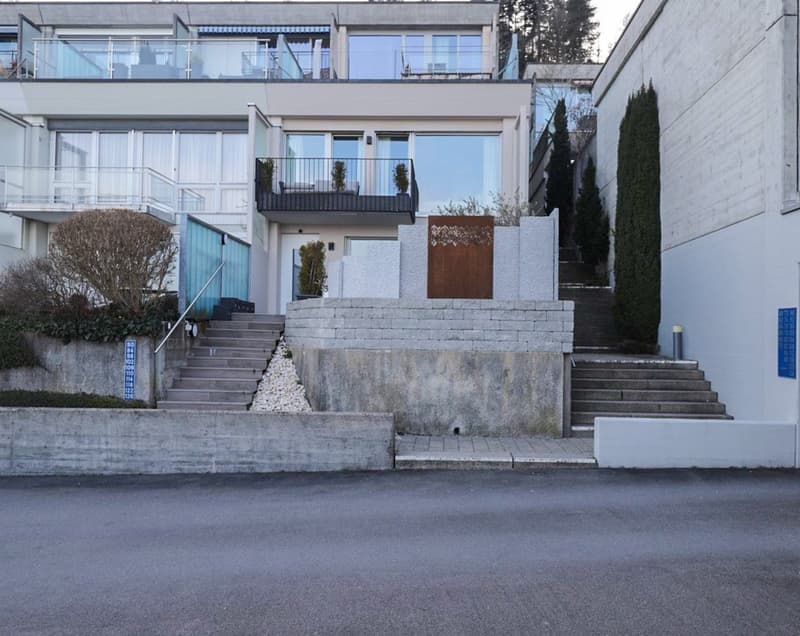 Modern 3-story house, white concrete, glass windows, brown railings, front stairs, terrace on second floor