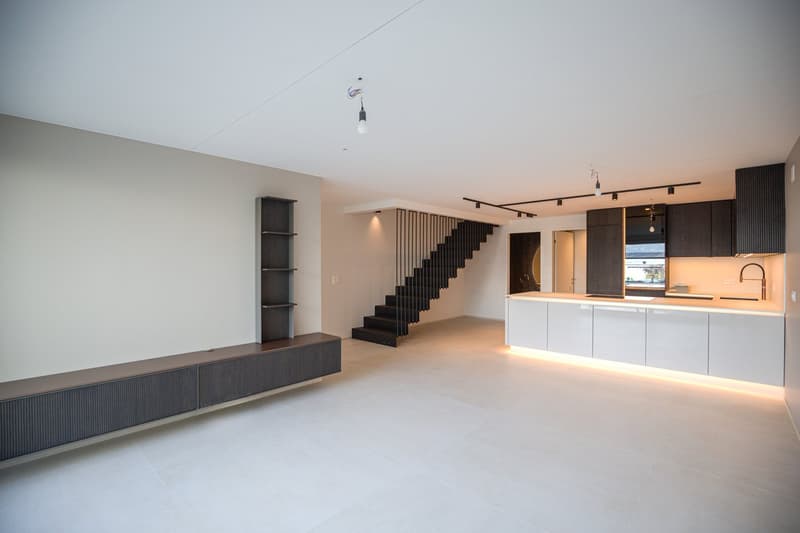 open kitchen with white cabinets, modern staircase, built-in shelves, tiled floor, minimalist design