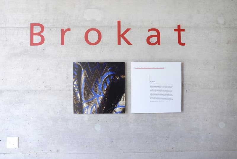Concrete wall with red text 'Brokat' and two posters