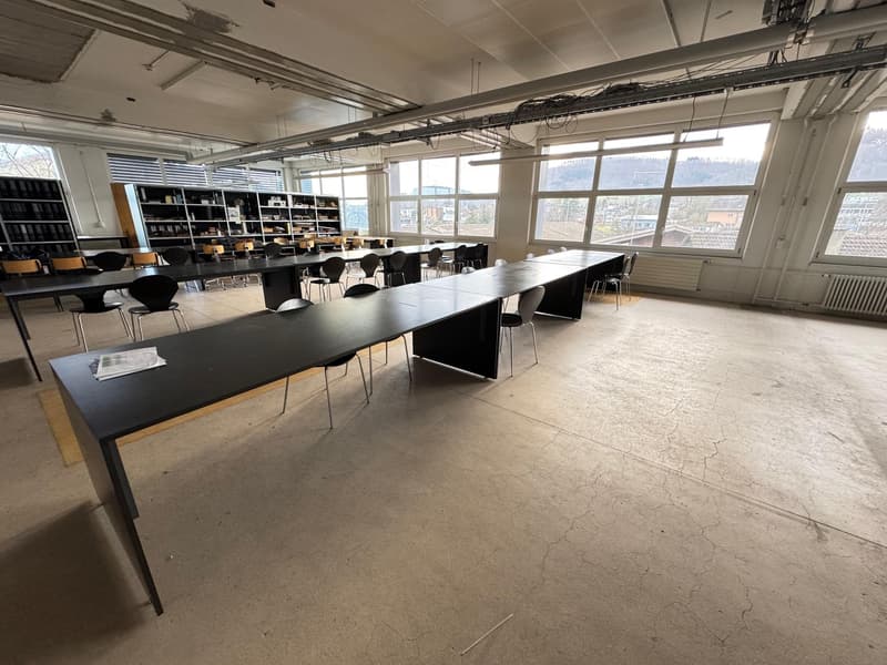 Empty conference room, long black tables, black and white chairs, large windows, bookshelves