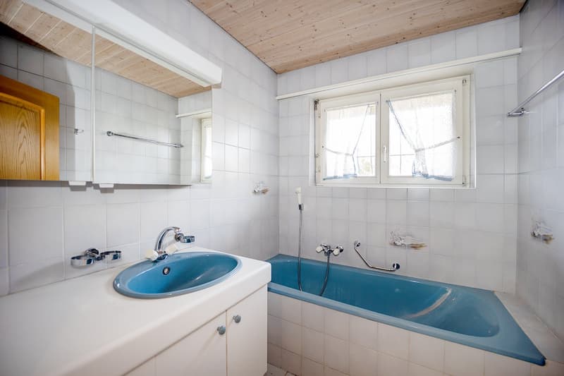 tiled floor and walls, sink with faucet, bathtub, mirror, wooden cabinet, window with curtains