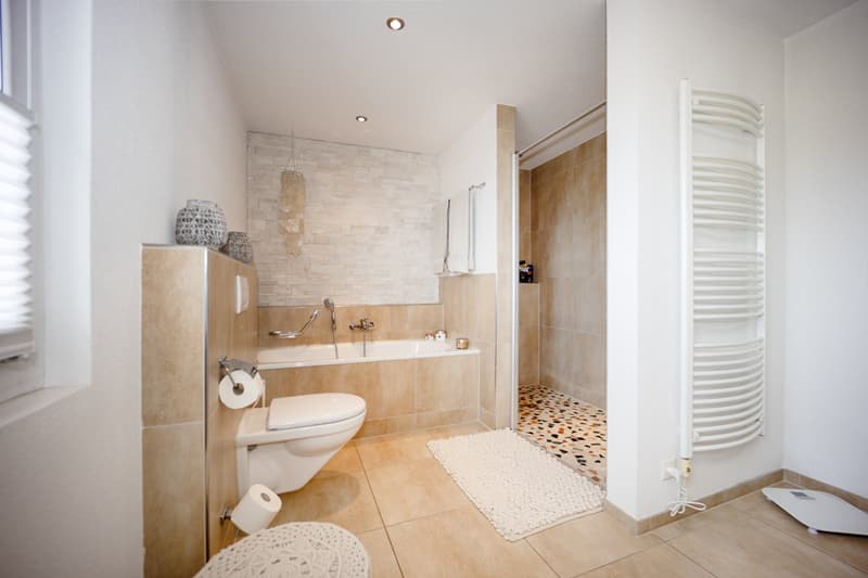 bathroom with bathtub, shower, toilet, towels, tile flooring