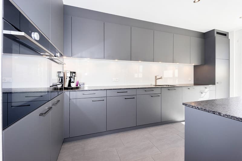 modern kitchen with gray cabinets, granite countertops, stainless steel appliances, under-cabinet lighting, and a dishwasher