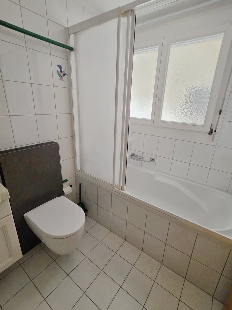 Bathroom with white tiles, white toilet, white bathtub, white shower curtain, white cabinet, white sink, white towel, white toilet paper, white wall, white window, white door, white floor