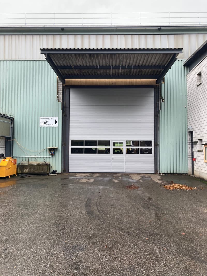 industrial building with a large roll-up door, a green wall and a white roll-up door.