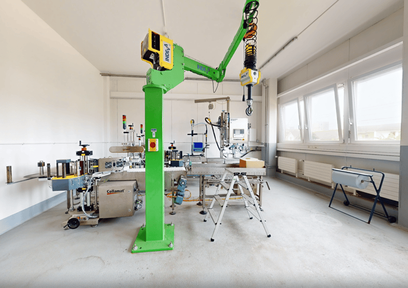 spacious room, white walls, industrial equipment, green robotic arm, industrial machines, ladders, windows, metal radiators
