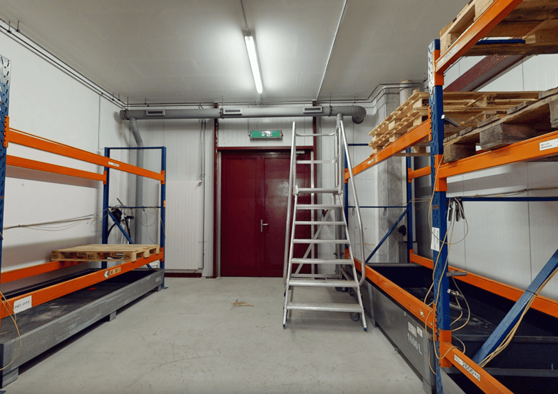 Metal shelving, industrial steel doors, warehouse ladder, storage units, ceiling lights, large door, storage pallets
