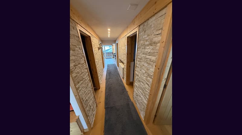 Wooden flooring, white and brown walls, three doorways, a carpeted section