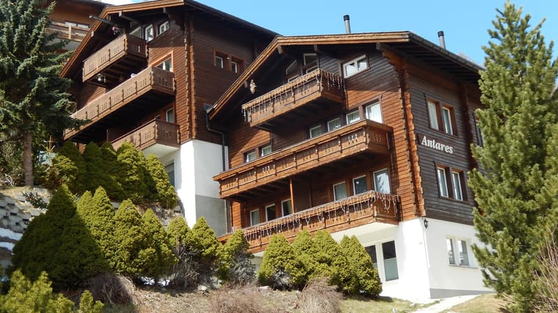 3 story wooden house, white trims, numerous balconies, on hill
