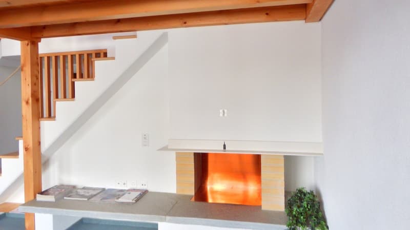 white walls, fireplace, wooden stairs, magazines on the table