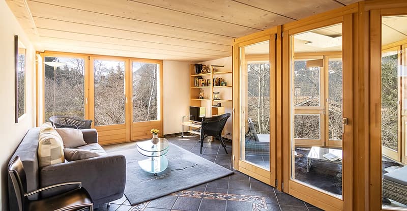 wooden ceiling, large windows, couch, coffee table, rug, shelves, black chairs