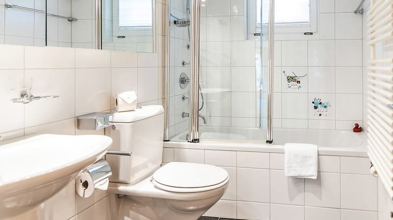 white tiles, white sink, white toilet, glass shower enclosure, bathtub, towel, mirror