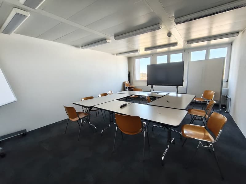 empty room with tables, chairs, whiteboard, and a television