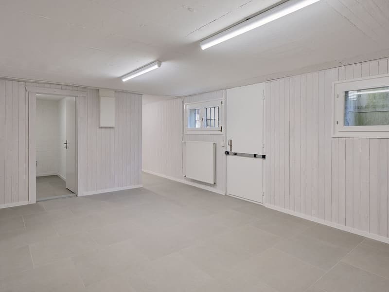 spacious basement room, white walls, tile flooring, recessed lights, doorways, small window