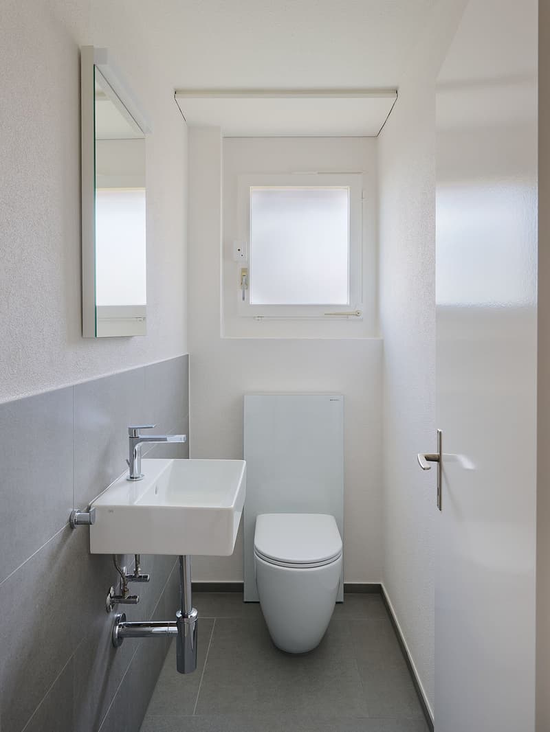 white sink, white toilet, mirror, white tiles, white walls