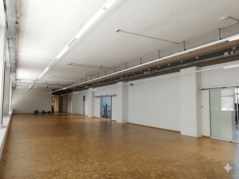 large open space, wooden floor, white walls, glass doors, metal beams