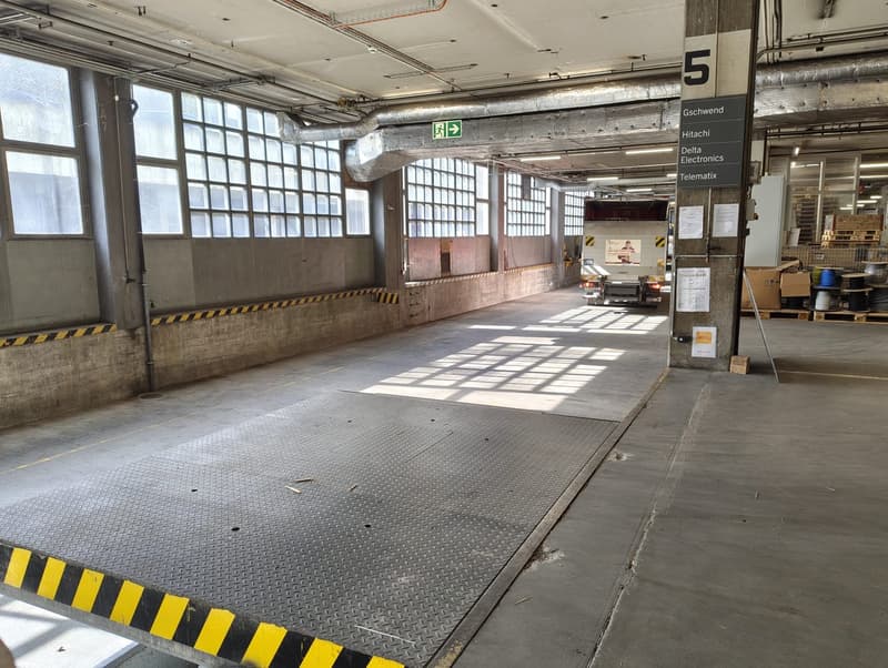 Empty parking lot with concrete floor, metal ramp, and large windows