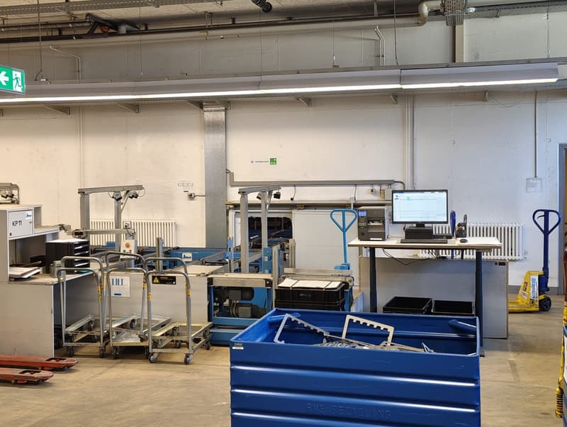 Industrial space with multiple machines, carts, and a desk with a computer