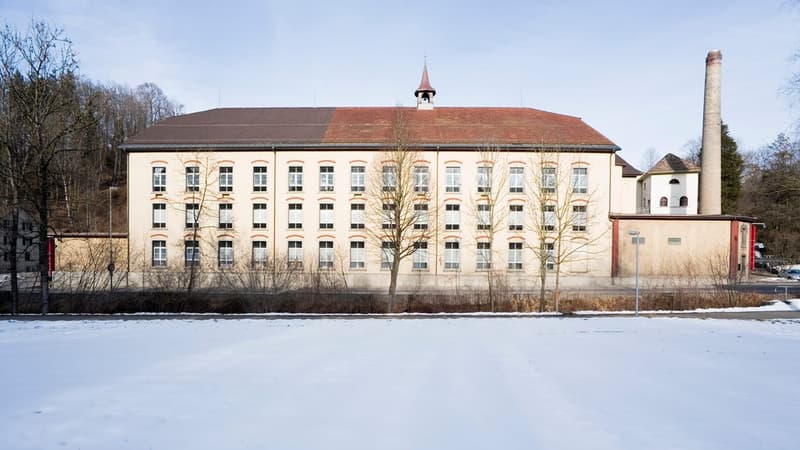 large building, many windows, red roof, tower, surrounded by fence, snow-covered ground