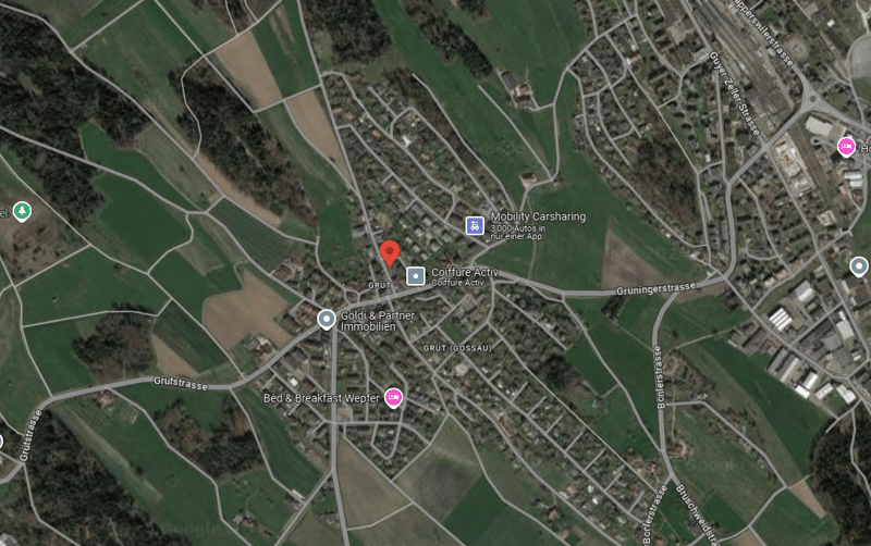 Aerial view of a residential area with houses, fields, and some commercial establishments. There is a car-sharing service, a clothing store, and a bed & breakfast mentioned on the map.