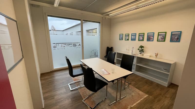 Meeting room with a table, chairs, a shelf, and a glass door.