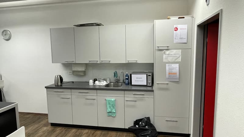 modern kitchen with white cabinets, granite countertop, stainless steel sink, microwave, refrigerator, and a trash bag