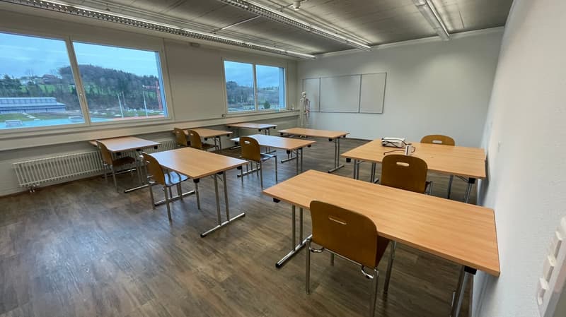 empty classroom with wooden desks, chairs, whiteboards, radiators, windows