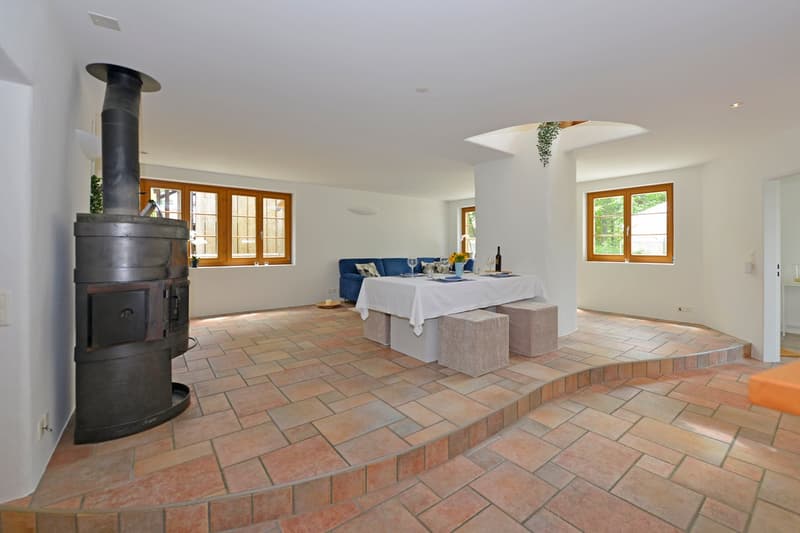 large room with fireplace, dining table, blue couch, wine glasses on table, brick flooring