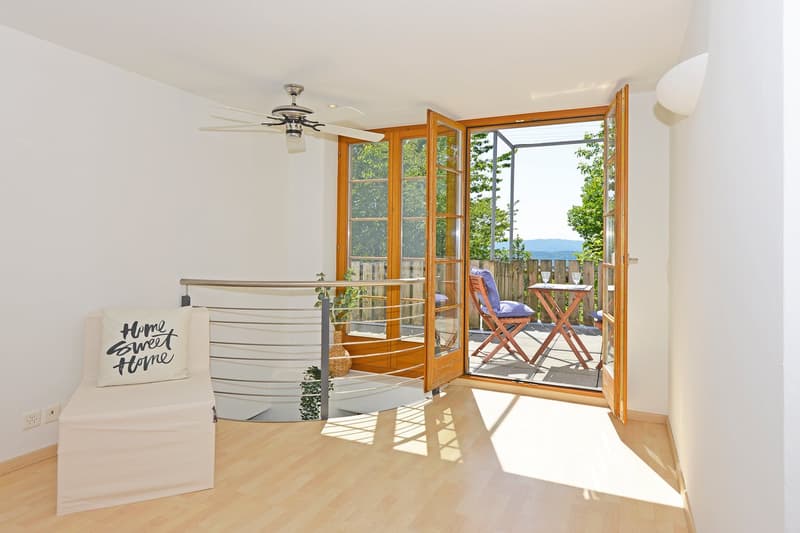 light room, hardwood floor, large windows, double doors to balcony, outdoor chairs, desk, ceiling fan