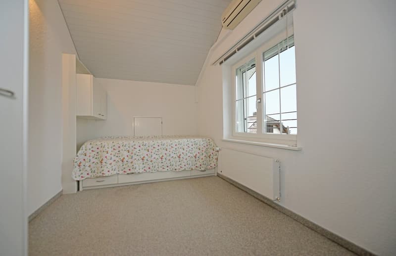 bedroom with storage under the bed, white walls, white ceiling, small window, white radiator