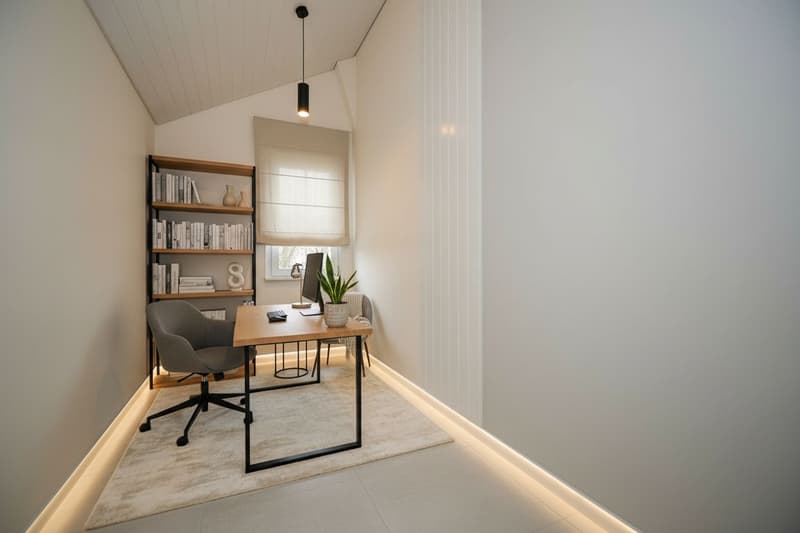 Corner office room with a desk, chair, bookcase, plants, and computer monitor. White walls and ceiling, beige floor, beige curtains, beige chair