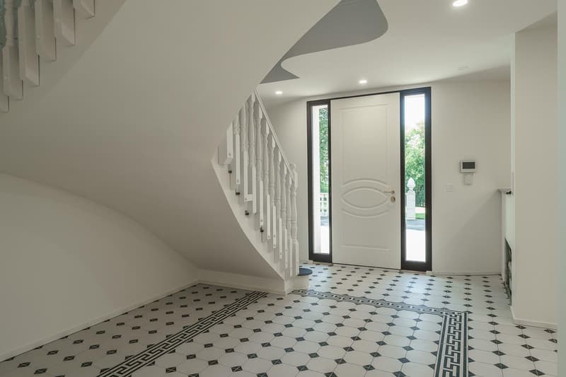 Raised ground floor, elegant tiled floor, modern white door, white walls, staircase