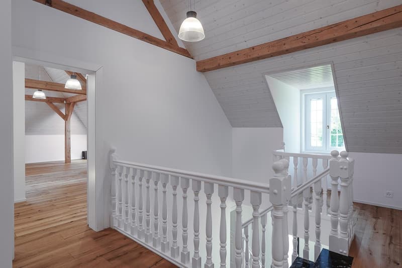 White wooden railing, wooden ceiling beams, hardwood floors