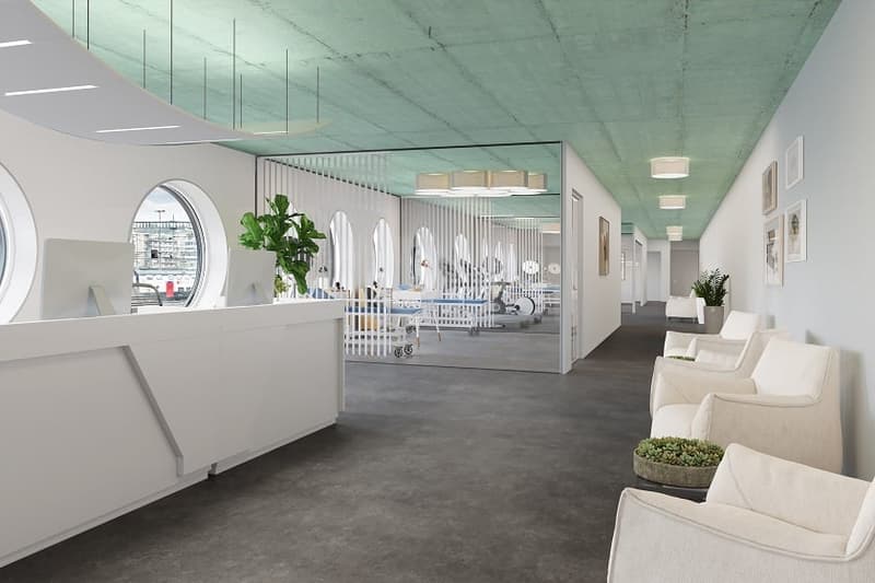 Spacious and modern office or commercial space with a reception area, comfortable seating, and glass partitions separating different sections. The space features a minimalist design with white walls, concrete flooring, and recessed lighting. A dishwasher