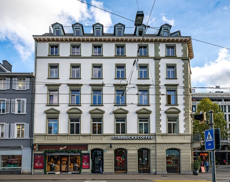 white facade, multiple windows, Starbucks Coffee shop on the ground floor, streetlights and wires above