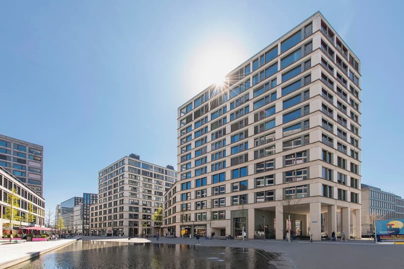 High-rise building with many windows, balconies, and a fountain in front