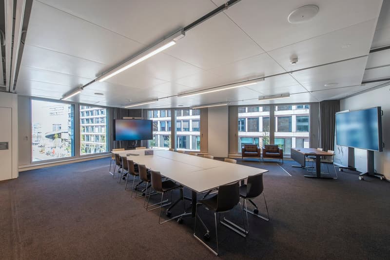 conference room with long table, chairs, monitors, carpeted floor, large windows