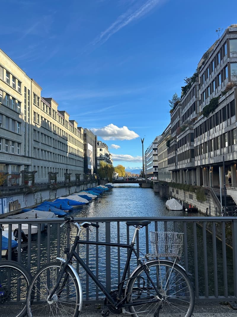 Buildings with balconies and boats docked along a canal under a clear blue sky.