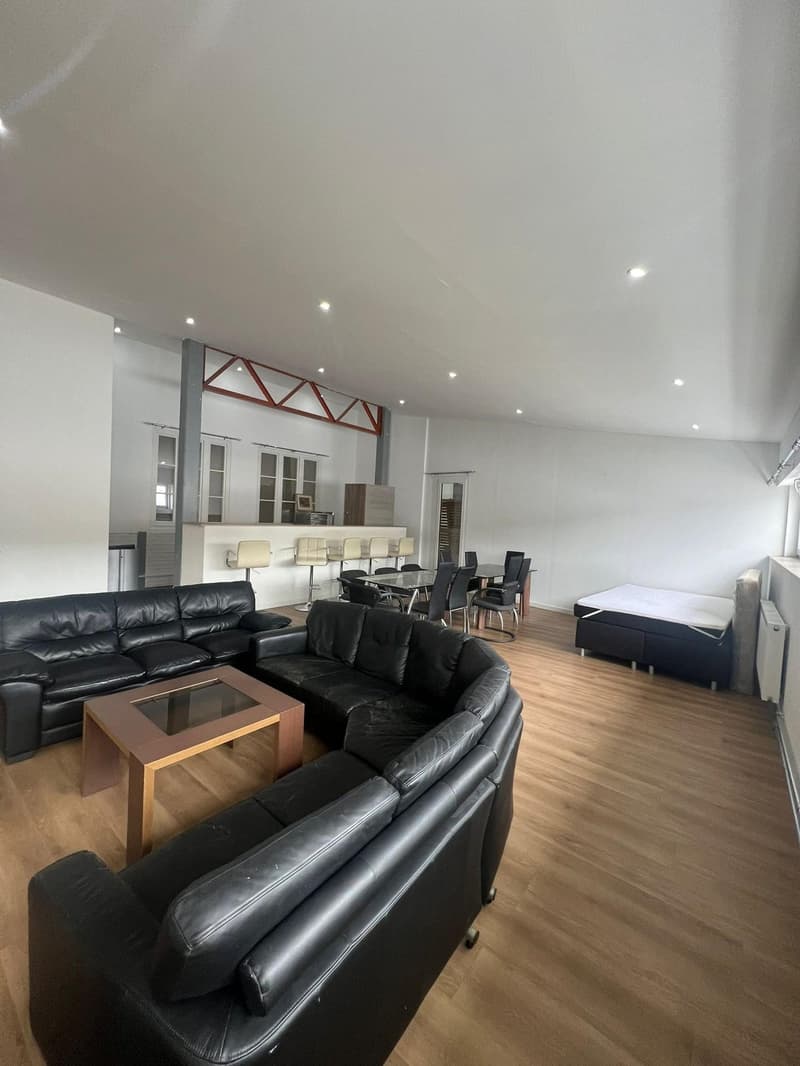 open plan living and dining room with leather sofas, center table, open plan kitchen, dining table with 8 chairs, additional sleeping area with bed, air conditioner, built-in cabinets, and wooden flooring